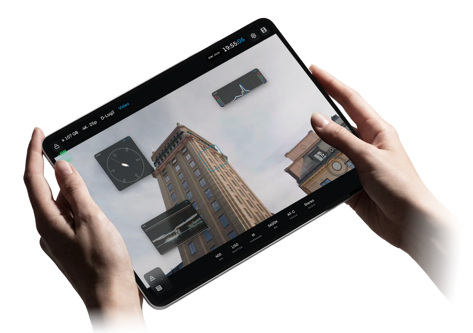 OpenPocketCine on an iPad Pro held in two hands, with waveform, histogram, and vectorscope over a Pocket 4 Pro city shot