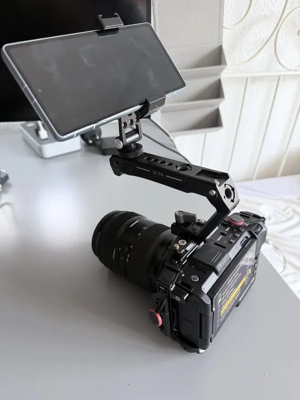 Phone secured above a Nikon ZR on a cage-mounted top handle.
